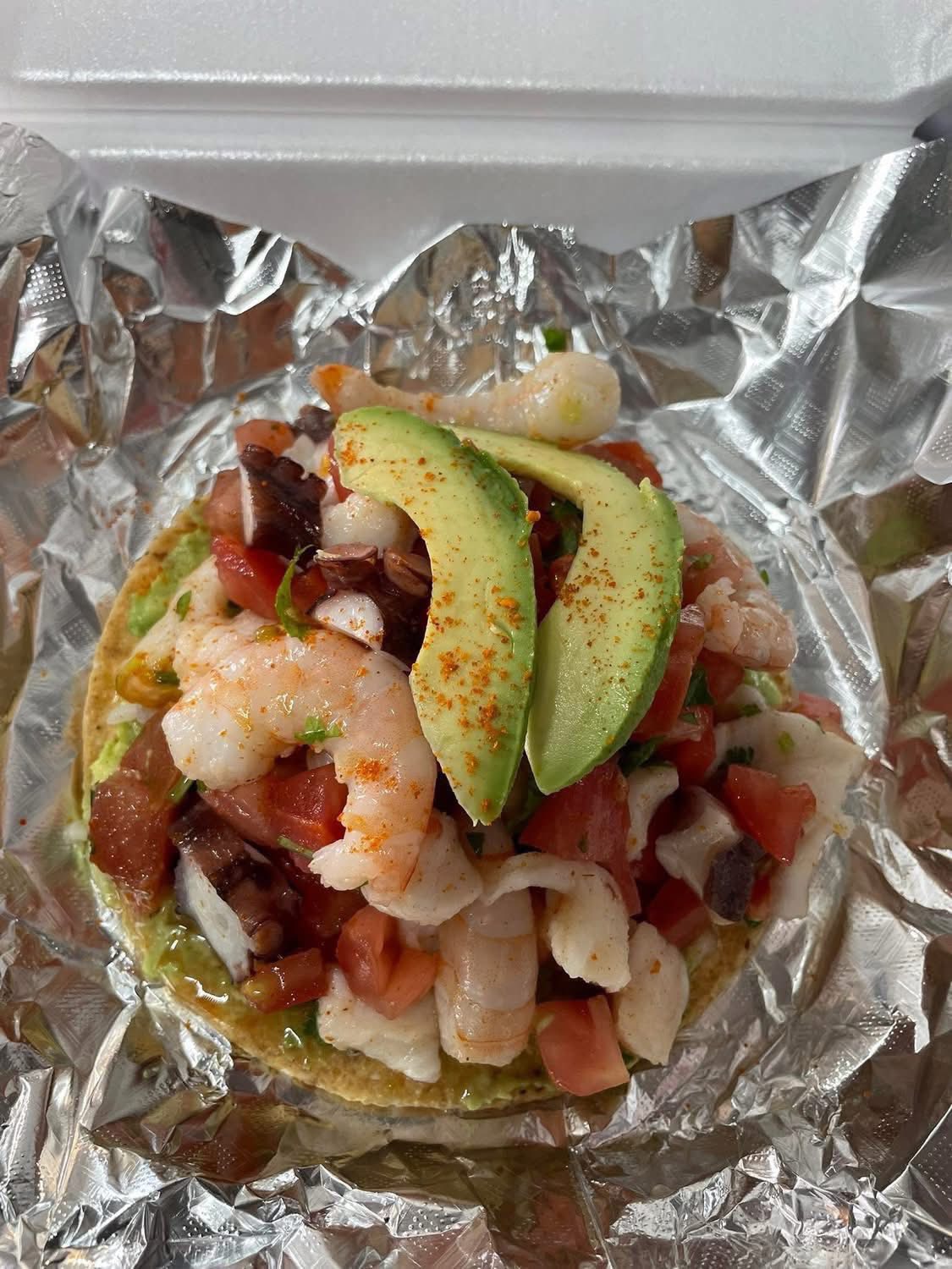 Mixed ceviche tostada topped with avocado